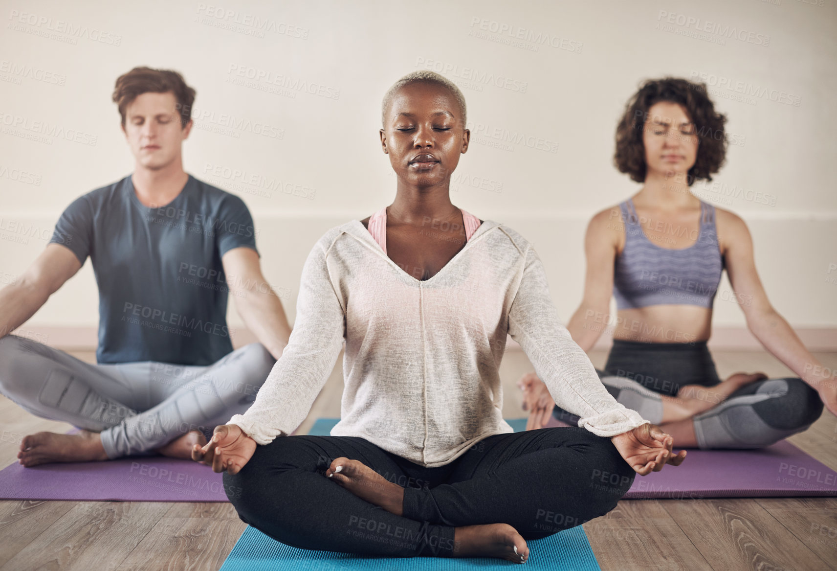 Buy stock photo Full length shot of a diverse group of yogis sitting together and meditating after an indoor yoga session