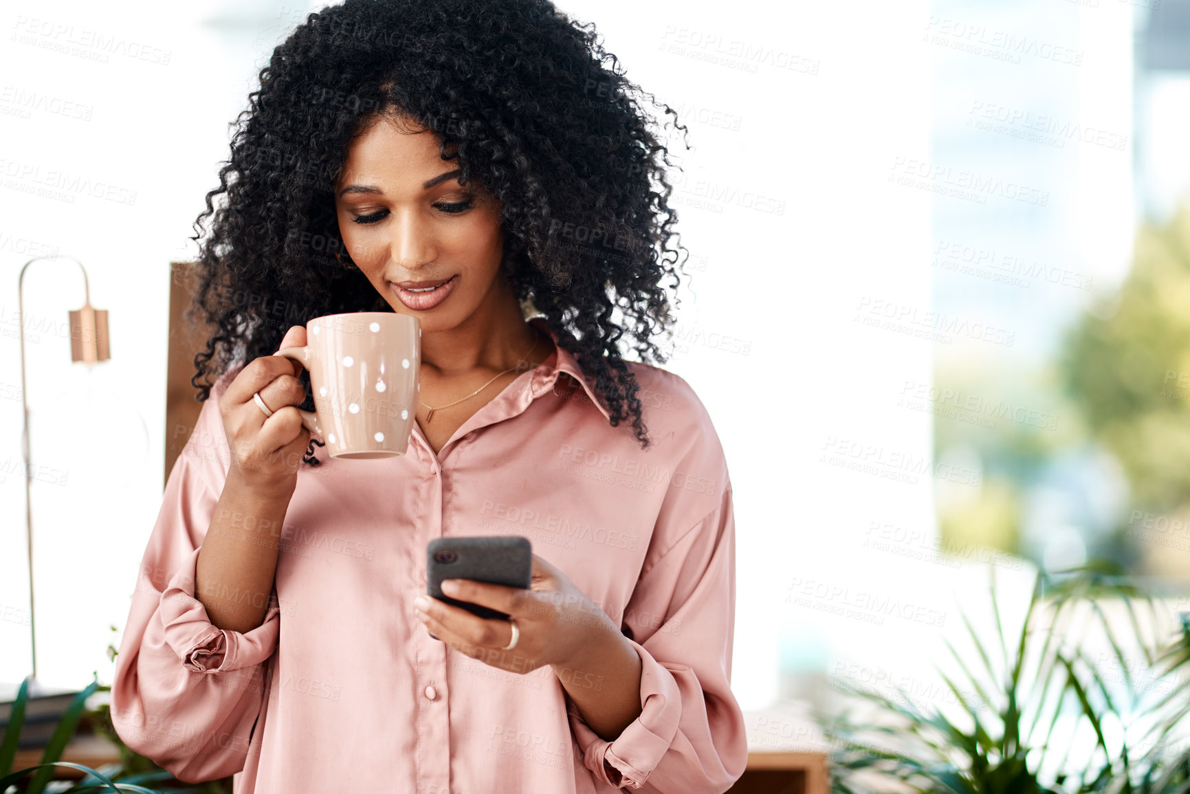 Buy stock photo Shot of a young businesswoman having coffee and using a smartphone in a modern office