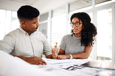 Buy stock photo Shot of a young businessman and businesswoman working on a blueprint in a modern office