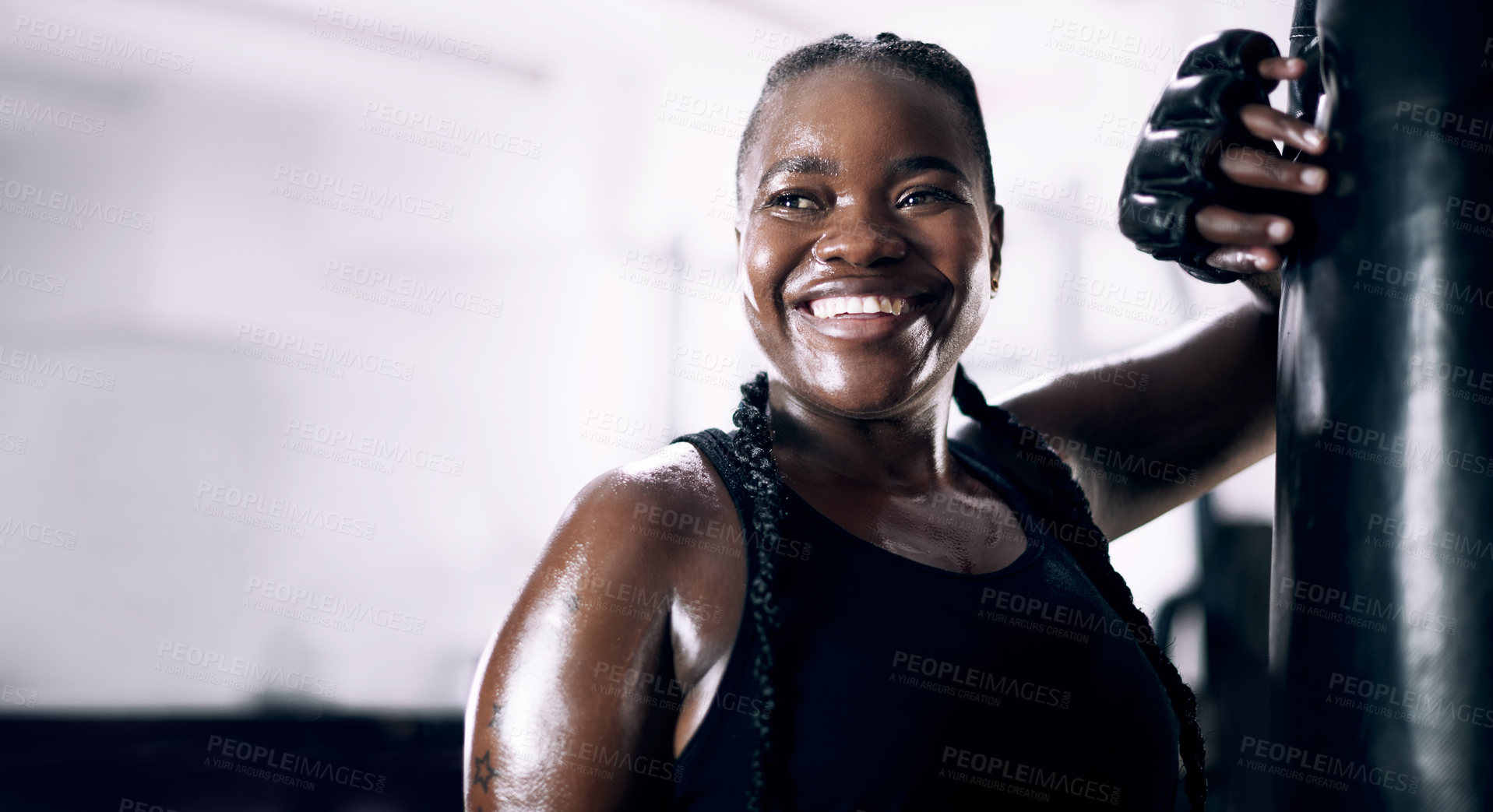 Buy stock photo Cropped shot of an attractive young female athlete leaning against a boxing bag in the gym