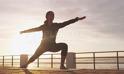 Buy stock photo Shot of a woman practising yoga on the promenade