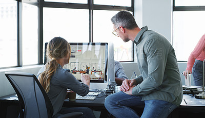 Buy stock photo Shot of a businessman and businesswoman having a discussion and using a computer together in a modern office