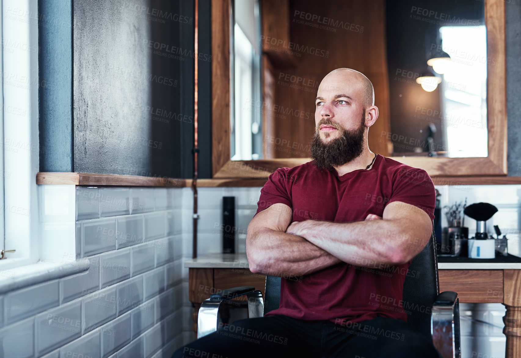 Buy stock photo Cropped shot of a handsome young barber posing with his arms folded inside his barbershop