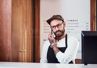 Buy stock photo Cropped shot of a handsome young barber making a phone call inside his barbershop