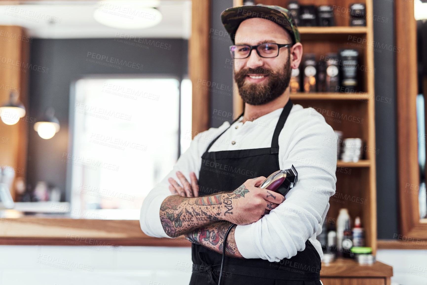 Buy stock photo Portrait of a handsome young barber posing with his arms folded inside his barbershop