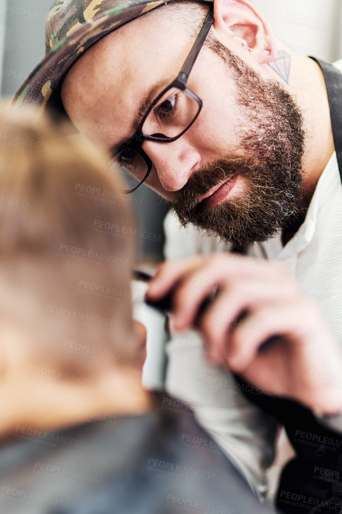 Buy stock photo Cropped shot of a handsome young barber giving a little boy a haircut inside a barbershop