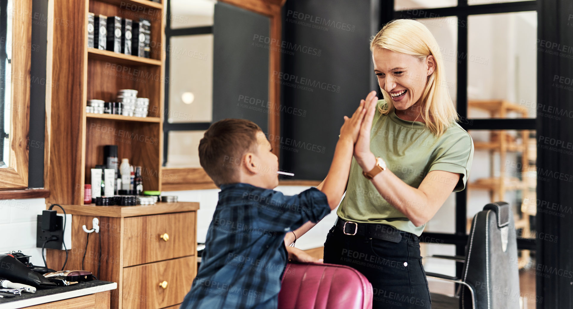 Buy stock photo Happy, kid and hairdresser in barbershop high five in chair for hair care, grooming and beauty. Professional, service and child with pride in salon, store and appointment with woman for hairstyle