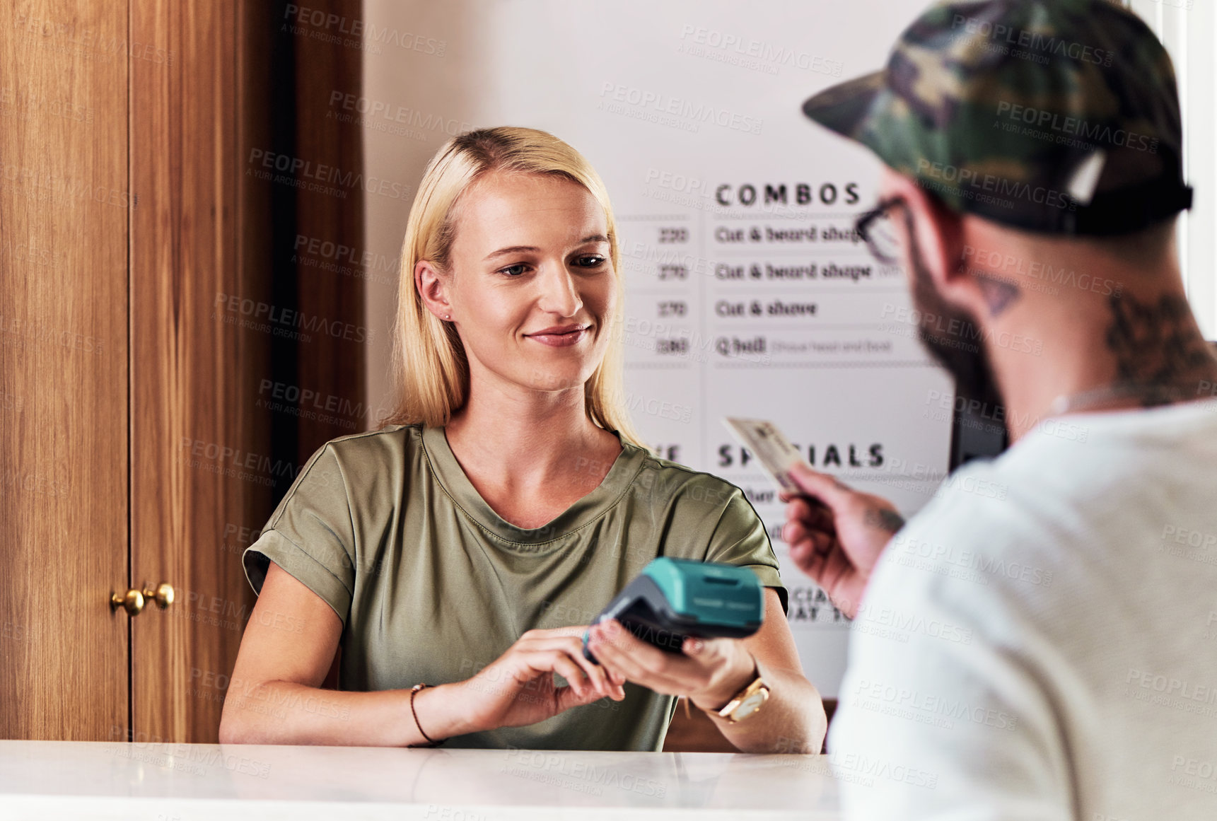 Buy stock photo Cropped shot of an attractive young hairdresser using a credit card machine to action a payment inside her salon
