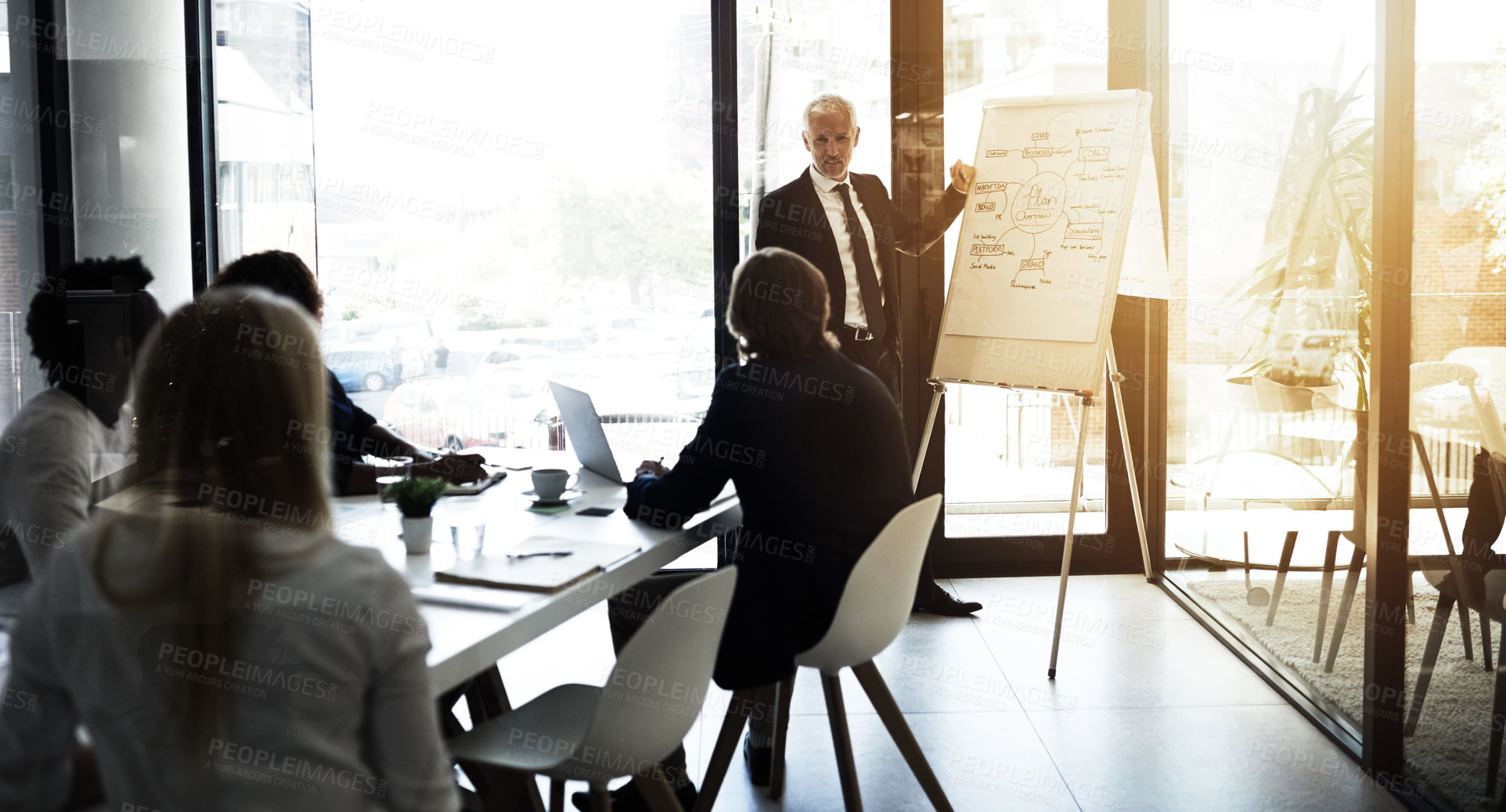 Buy stock photo Shot of a mature businessman giving a presentation to colleagues in a boardroom