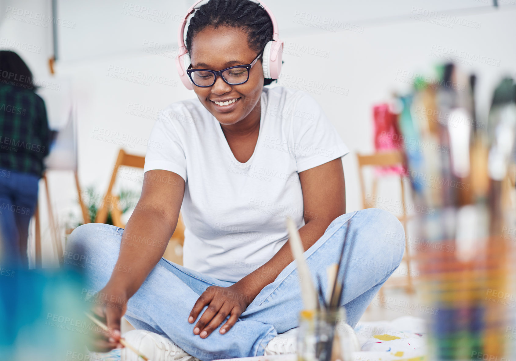 Buy stock photo Shot of a young woman wearing headphones while painting in a art studio