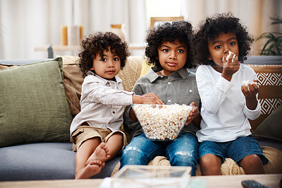 Buy stock photo Cropped shot of three adorable little boys eating popcorn and watching movies together at home