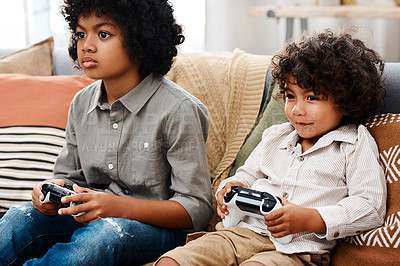 Buy stock photo Cropped shot of two adorable little boys sitting on a sofa and playing video games together at home