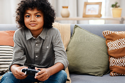 Buy stock photo Cropped shot of an adorable little boy sitting on a sofa and playing video games at home