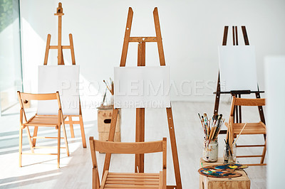 Buy stock photo Cropped shot of a group of easels and blank canvases in an empty art studio before a painting class