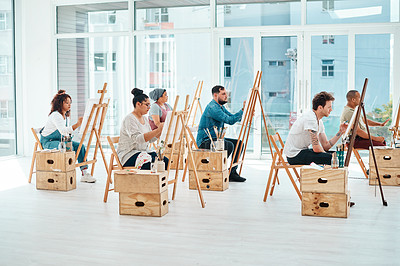 Buy stock photo Full length shot of a diverse group of artists sitting together and painting during an art class in a studio