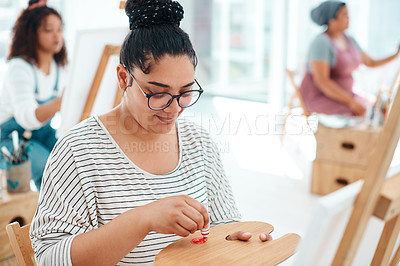 Buy stock photo Cropped shot of an attractive young artist squeezing paint onto a palette during an art class in the studio