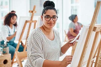 Buy stock photo Cropped portrait of an attractive young woman sitting with her friends and painting during an art class in the studio