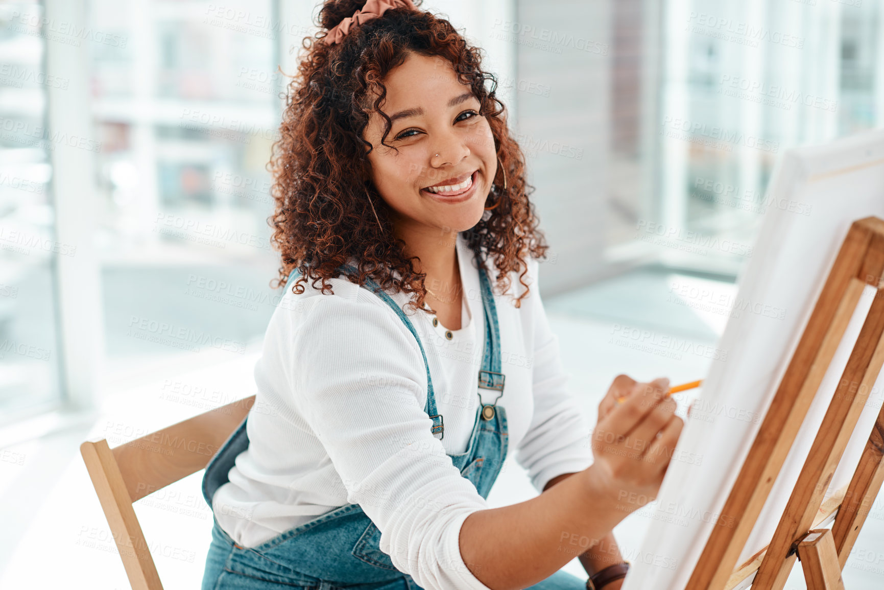 Buy stock photo Cropped portrait of an attractive young artist sitting alone and painting during an art class in the studio