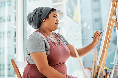 Buy stock photo Cropped shot of an attractive young artist sitting alone and painting during an art class in the studio