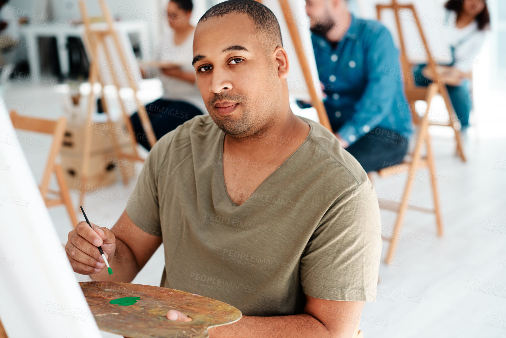 Buy stock photo Cropped portrait of a handsome young artist holding a palette during an art class in the studio