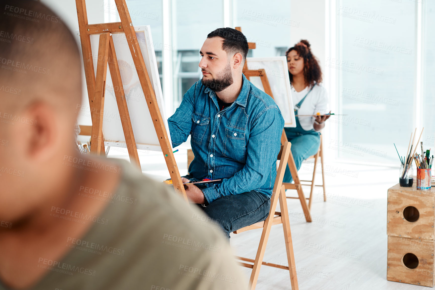 Buy stock photo Cropped shot of a handsome young artist sitting and painting during an art class in the studio