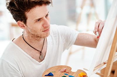 Buy stock photo Cropped shot of a handsome young artist sitting alone and painting during an art class in the studio