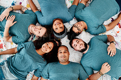 Buy stock photo High angle portrait of a diverse group of friends lying down in a circle during an art class