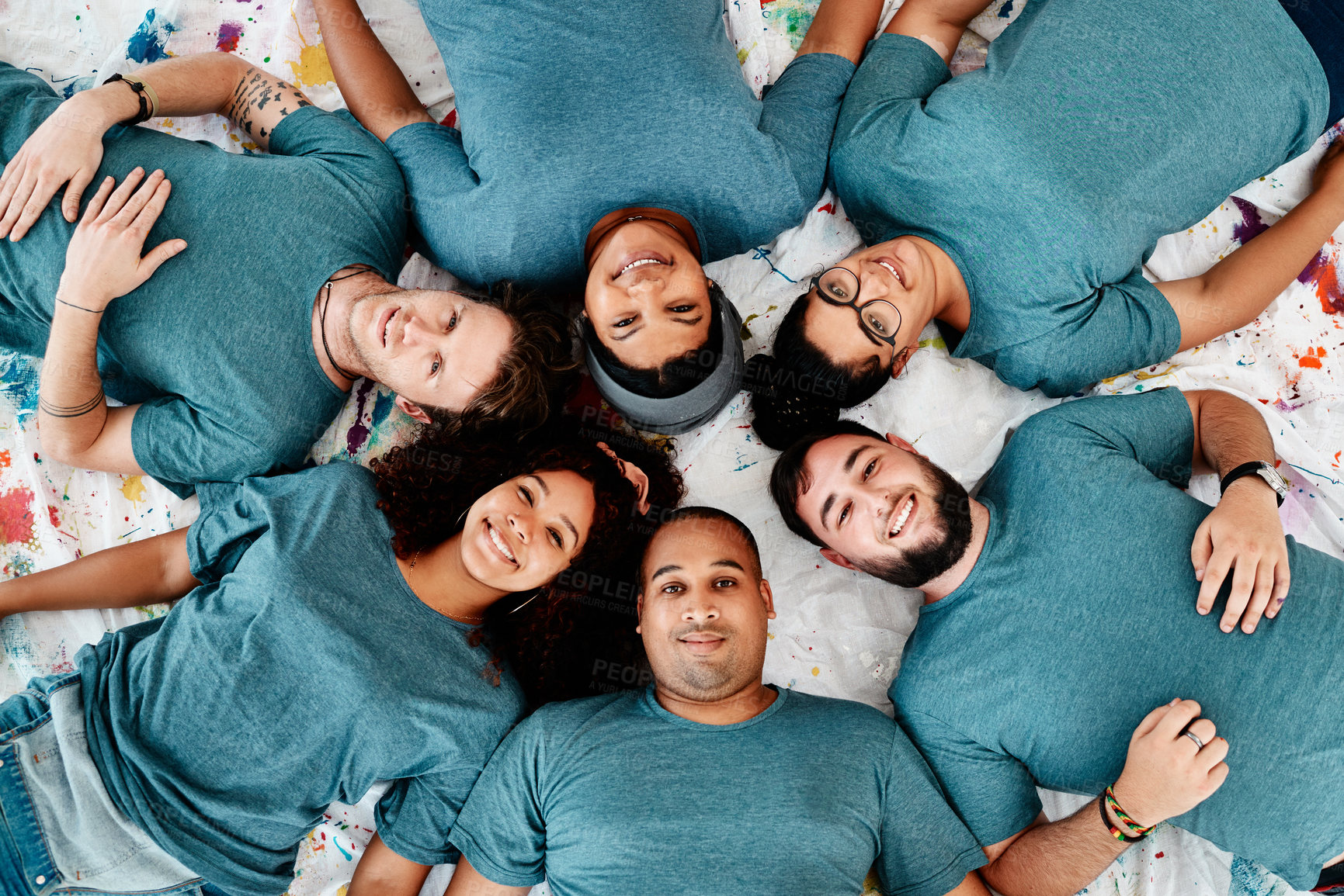 Buy stock photo High angle portrait of a diverse group of friends lying down in a circle during an art class