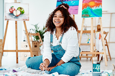 Buy stock photo Full length portrait of an attractive young artist sitting alone and painting during an art class in the studio
