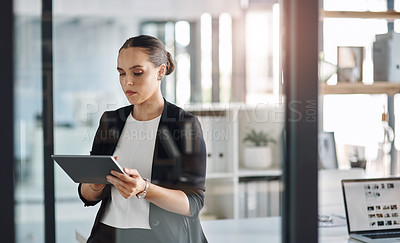 Buy stock photo Cropped shot of an attractive young businesswoman using a digital tablet inside her office
