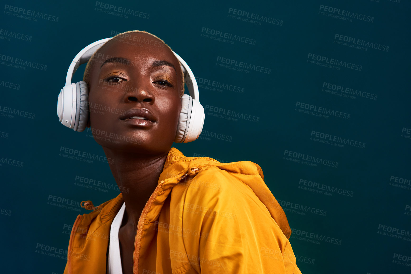 Buy stock photo Cropped portrait of an attractive young sportswoman standing alone and posing with headphones on against a dark studio background