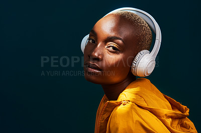 Buy stock photo Cropped portrait of an attractive young sportswoman standing alone and posing with headphones on against a dark studio background