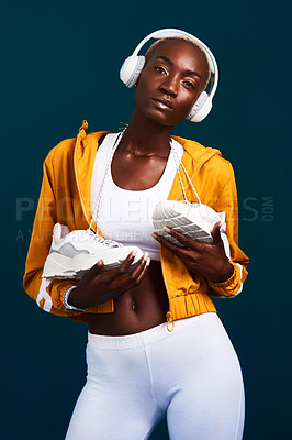 Buy stock photo Cropped portrait of an attractive young sportswoman standing alone and posing with headphones on against a dark studio background