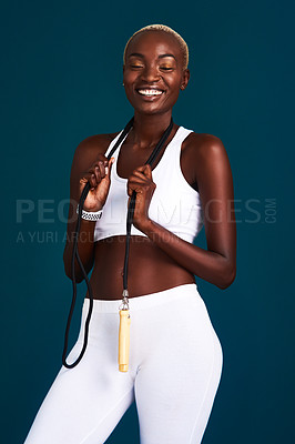 Buy stock photo Cropped shot of an attractive young sportswoman standing alone and posing with a jump rope against a dark background