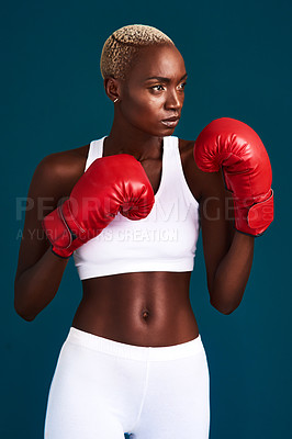 Buy stock photo Cropped shot of an attractive young female boxer working out against a dark background in the studio
