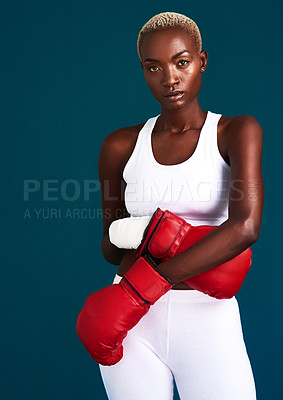 Buy stock photo Cropped portrait of an attractive young female boxer standing with her boxing gloves against a dark background