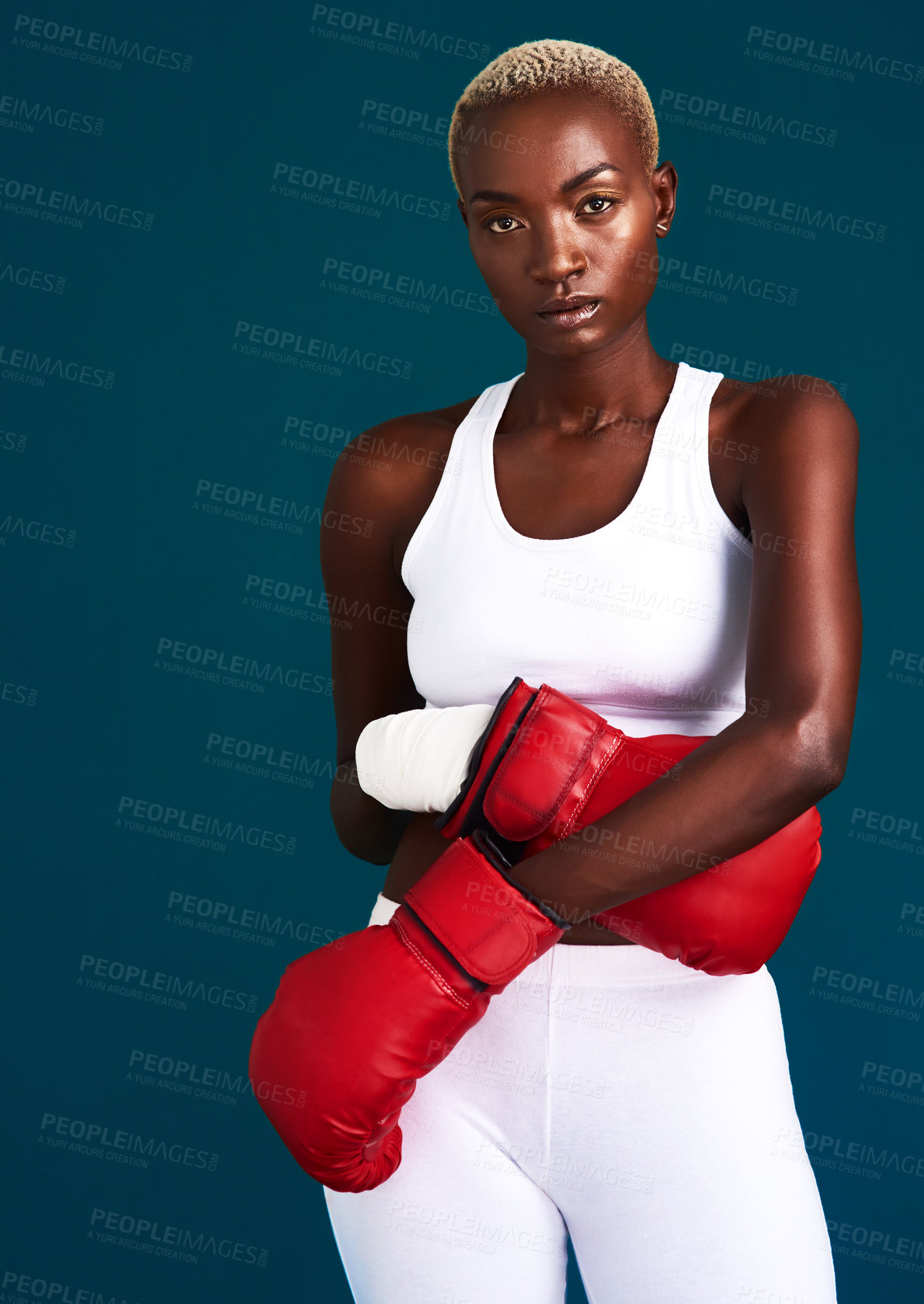 Buy stock photo Cropped portrait of an attractive young female boxer standing with her boxing gloves against a dark background