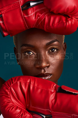 Buy stock photo Cropped portrait of an attractive young female boxer standing with her boxing gloves against a dark background