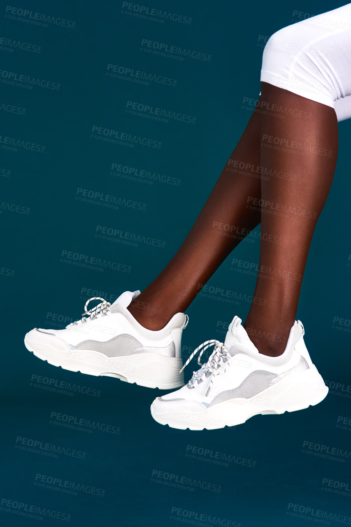 Buy stock photo Cropped shot of an unrecognizable sportswoman wearing her sneakers before working out against a dark background in the studio