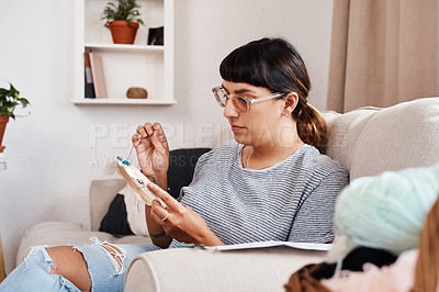 Buy stock photo Shot of a beautiful young woman doing embroidery at home