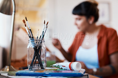 Buy stock photo Defocused shot of a young woman painting at home