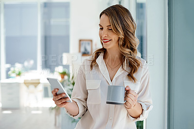 Buy stock photo Cropped shot of an attractive young businesswoman drinking coffee and using her cellphone inside of an office