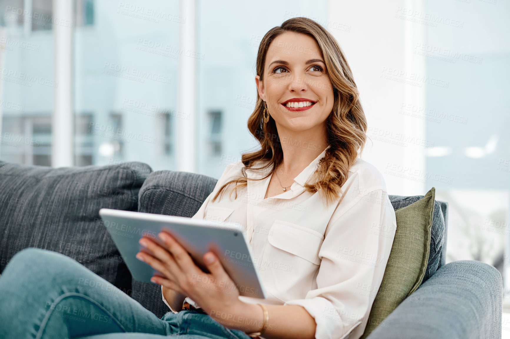 Buy stock photo Portrait of an attractive young businesswoman using a digital tablet while sitting on a sofa inside her office