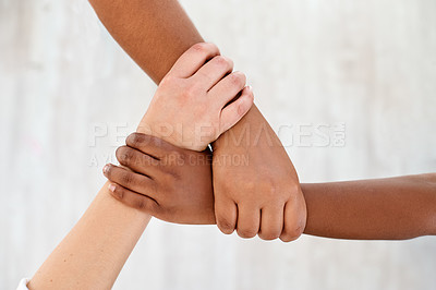 Buy stock photo Cropped shot of three unrecognizable businesswomen holding one another around the wrist against a gray background