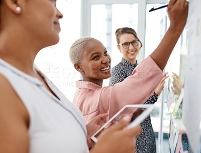 Buy stock photo Shot of a group of businesswomen brainstorming with notes on a glass wall in an office