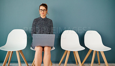 Buy stock photo Studio portrait of an attractive young businesswoman using a laptop while sitting in line against a grey background