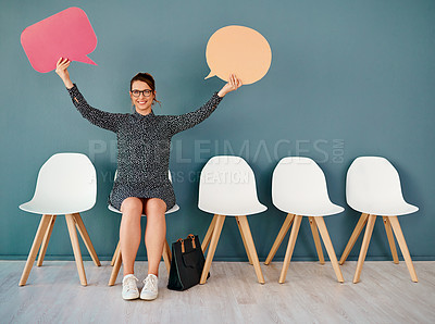 Buy stock photo Studio portrait of an attractive young businesswoman holding up speech bubbles while sitting in line against a grey background