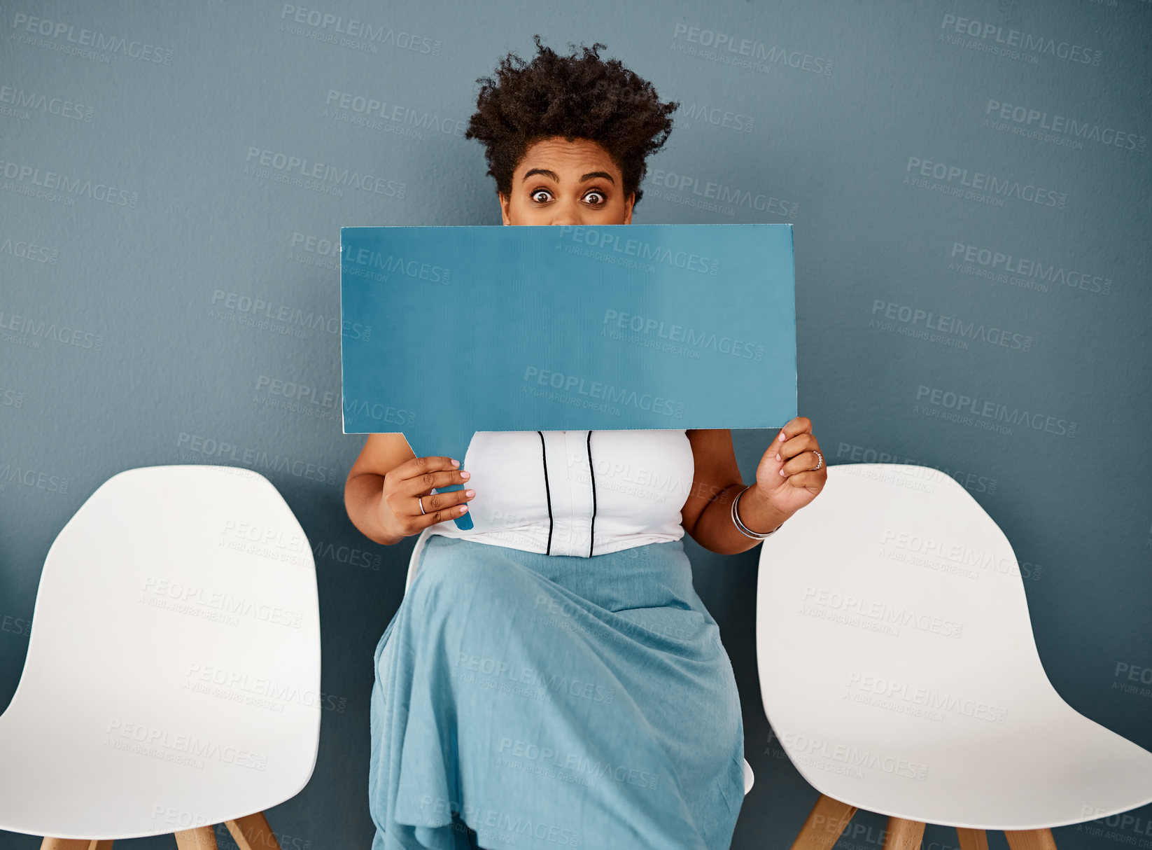 Buy stock photo Studio portrait of an attractive young businesswoman covering her face with a speech bubble while sitting against a grey background