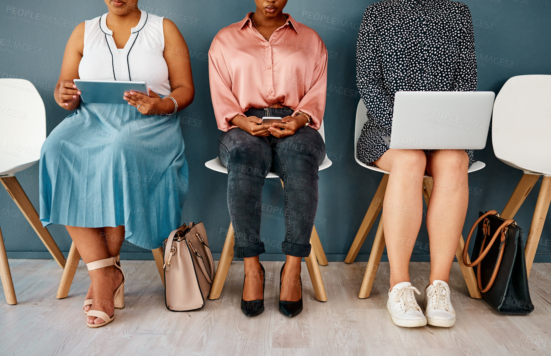 Buy stock photo Studio shot of a group of unrecognizable businesswomen using wireless technology while sitting in line against a grey background