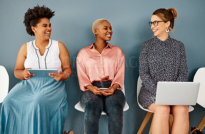Buy stock photo Studio shot of a group of attractive young businesswomen laughing together while sitting in line against a grey background